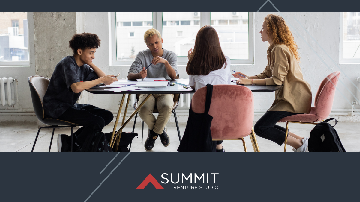 Four professionals seated around a table in a bright office collaborating during a discussion.