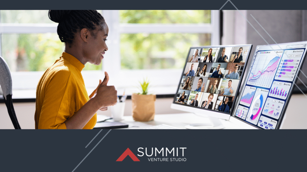 A woman participates in a virtual meeting from her desk, giving a thumbs-up while viewing a multi-person video call and data analytics dashboards on dual monitors, with the Summit Venture Studio branding below.