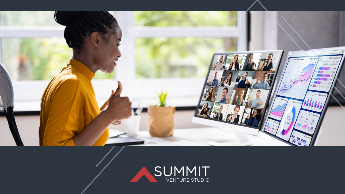 A woman participates in a virtual meeting from her desk, giving a thumbs-up while viewing a multi-person video call and data analytics dashboards on dual monitors, with the Summit Venture Studio branding below.